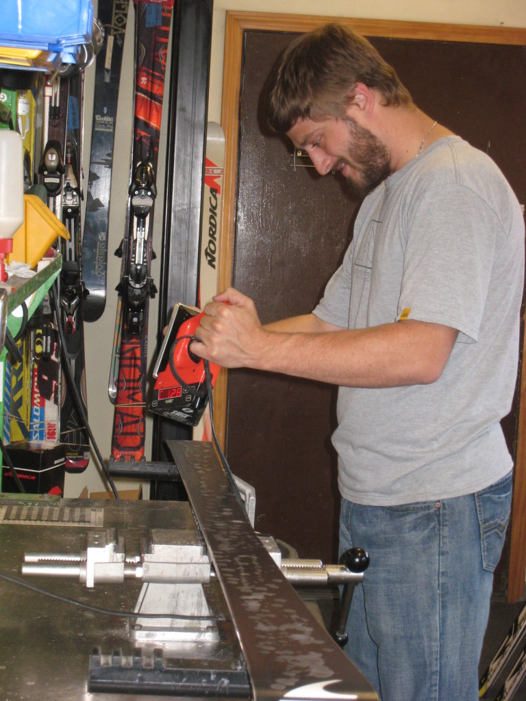David from Peak Ski Shop applying summer ski wax on a pair of skis prior to storage.